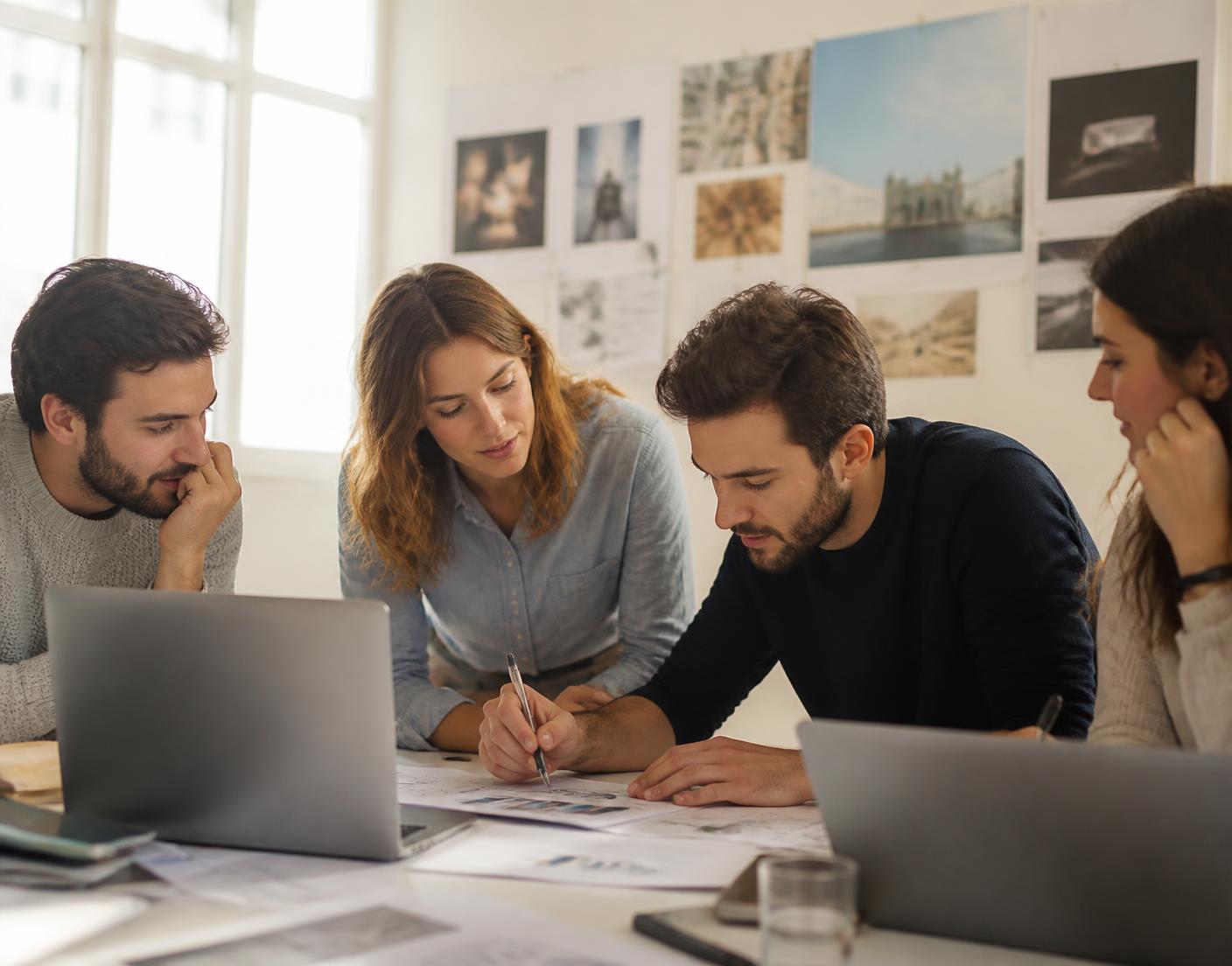 Team di un'agenzia al lavoro su report stampati e laptop attorno a un tavolo